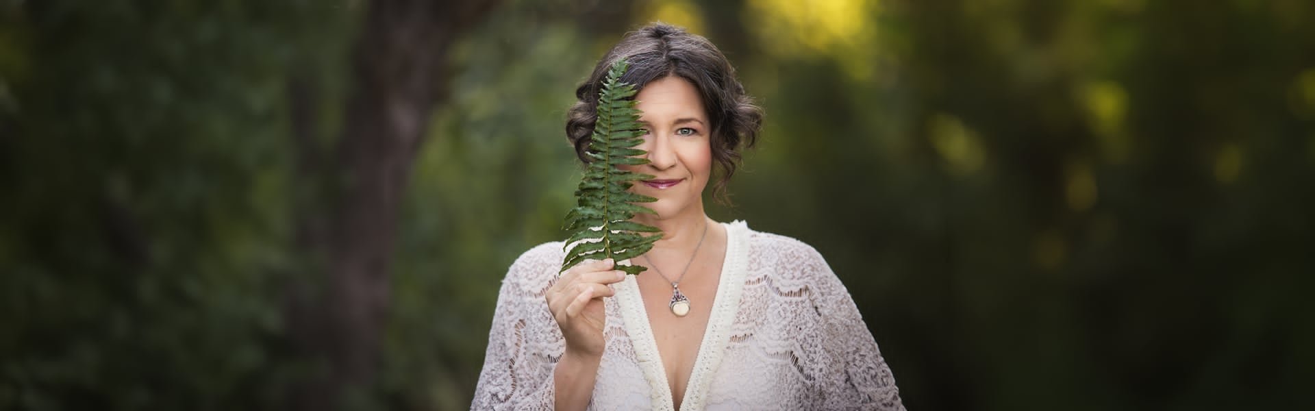 Mandy Kuelz holding a fern in front of her face, smiling